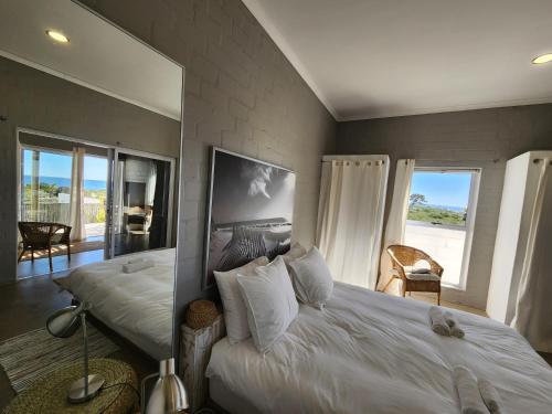 a bedroom with a large white bed and a mirror at Mirage-Beach Apartment in St Helena Bay