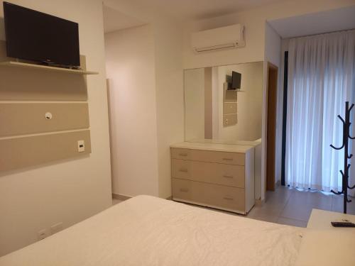 a bedroom with a bed and a dresser with a mirror at Maravilhoso Apartamento Reserva DNA Ubatuba in Ubatuba