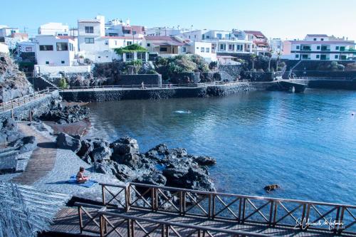 a woman sitting on the rocks in a body of water at La Casita a 60 pasos del mar in Tamaduste