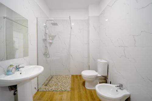 a white bathroom with a sink and a toilet at Apartamente Tirana in Tirana