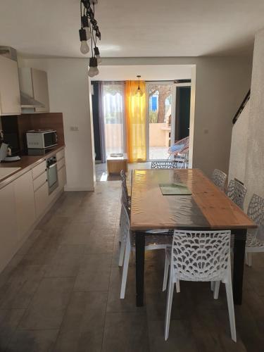 une cuisine et une salle à manger avec une table et des chaises en bois dans l'établissement Maison 8 personnes St pierre la mer, à Fleury