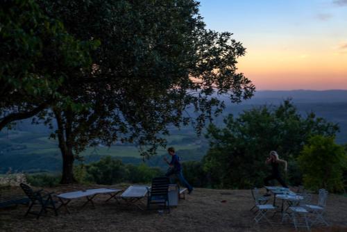 un hombre y una mujer de pie en una colina con sillas y mesas en Agriturismo Cetamura en Castelnuovo Berardenga