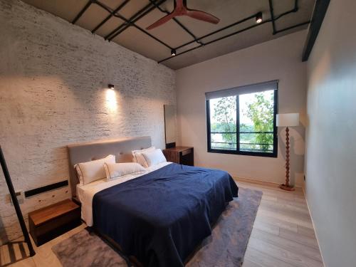 a bedroom with a bed with a blue blanket and a window at VAUX Park Street - A collection of 8 luxury lofts in Colombo