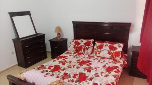1 dormitorio con 1 cama con manta roja y blanca en الحي المحمدي آسفي, en Safí