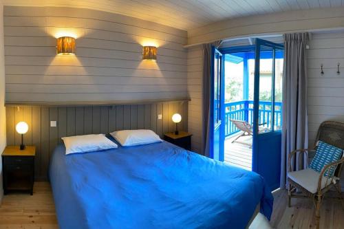 une chambre avec un lit bleu et un balcon dans l'établissement La maison aux Volets Bleus - Plage des Américains, à Lège-Cap-Ferret