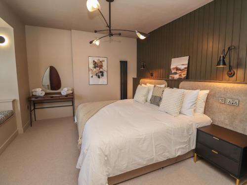 a bedroom with a large white bed and a table at Glencoe House in Wooler