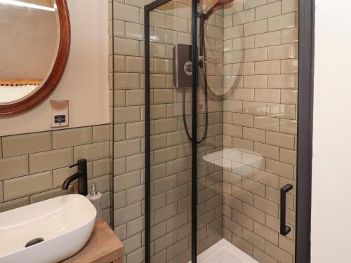 a shower in a bathroom with a sink and a mirror at Glencoe House in Wooler