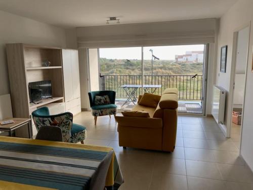 d'un salon avec un canapé et des chaises ainsi que d'un balcon. dans l'établissement Appartement cosy proche de la mer, à Neufchâtel-Hardelot