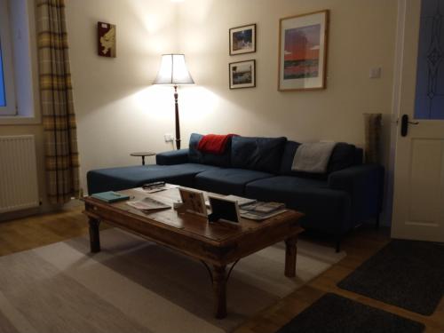 Sala de estar con sofá azul y mesa de centro en Snowberry Cottage, en Borve