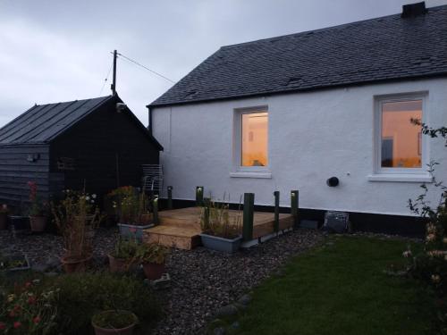 a white house with a garden in front of it at Snowberry Cottage in Borve