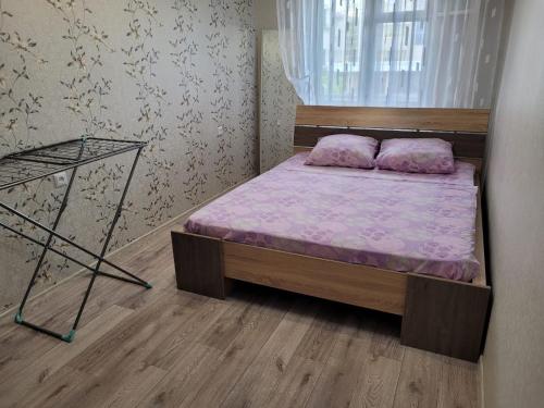 een kleine slaapkamer met een bed en een raam bij Апартаменты Гоголя 46 in Karagandy