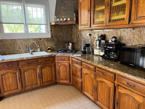 La cuisine est équipée de placards en bois, d'un évier et d'un four micro-ondes. dans l'établissement Villa lumineuse et spacieuse, à Lorgues