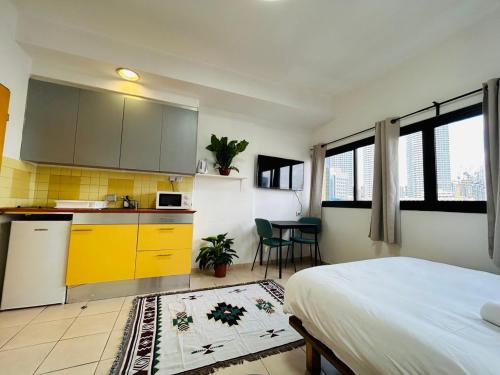 a kitchen with yellow cabinets and a bed in a room at Lev Florentin Apartments - Montefiore TLV in Tel Aviv