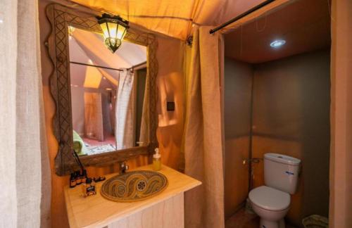 a bathroom with a sink and a mirror and a toilet at Enjoy Luxury Camp in Merzouga