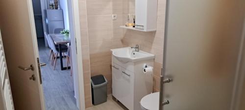 a bathroom with a toilet and a sink and a table at Apartman La-iv in Bjelovar