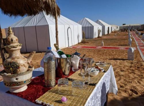 a table on a sandy beach with a tableablishthritisthritisthritisthritisthritisthritis at Enjoy Luxury Camp in Merzouga