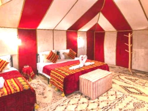 a bedroom with two beds and a room with red walls at Enjoy Luxury Camp in Merzouga