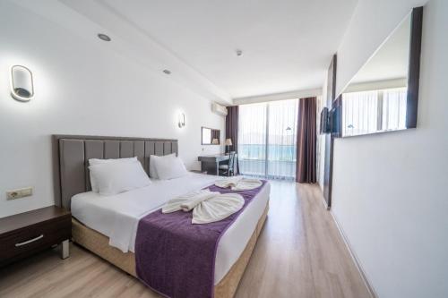 een slaapkamer met een groot bed en een paarse deken bij SUPREME BEACH İÇMELER Adults Only in Marmaris