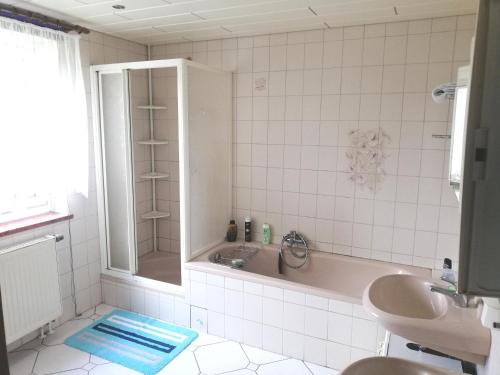 een badkamer met een bad, een wastafel en een douche bij Ferienwohnung Sonnenblume in Pfaffroda