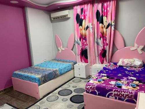 Assuit ultra modern apartment في أسيوط: سريرين في غرفة وردية وأرجوانية