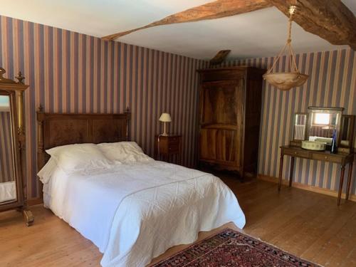 a bedroom with a white bed and striped walls at Buisson gîte et chambre d'hôte in Laruscade
