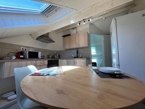 une cuisine avec une table en bois avec des chaises et un réfrigérateur dans l'établissement Charmant appartement sous les toits, à Périgueux