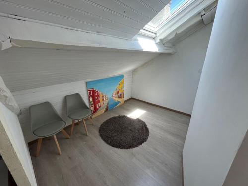 Cette chambre mansardée comprend deux chaises et un tapis. dans l'établissement Charmant appartement sous les toits, à Périgueux
