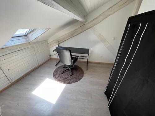Cette chambre mansardée comprend un bureau et une chaise. dans l'établissement Charmant appartement sous les toits, à Périgueux