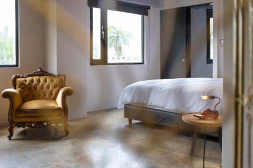 a bedroom with a bed and a chair and a table at Tomato TTT 番茄行旅 in Taipei
