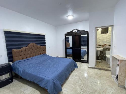 a bedroom with a bed with a blue comforter and a mirror at منتجع وشالية السفينة الريفي in Ajloun