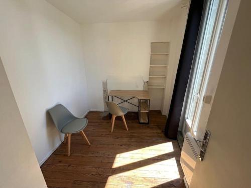 - un couloir avec deux chaises et une table dans une chambre dans l'établissement Charmant appartement avec balcon proche du centre., à Périgueux