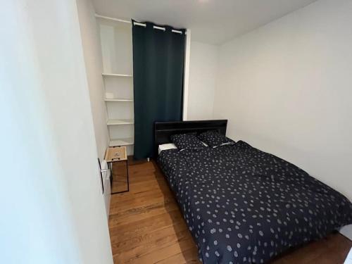 une chambre avec un lit noir et un rideau bleu dans l'établissement Charmant appartement avec balcon proche du centre., à Périgueux