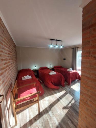 a bedroom with three beds with red sheets at Emilia II in Esquel