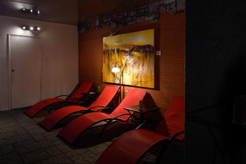 a row of red chairs in a room with a painting at Hôtel-La Grande Maison et Spa in Baie-Saint-Paul