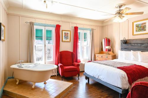 a bedroom with a bed and a tub and a chair at Hôtel-La Grande Maison et Spa in Baie-Saint-Paul