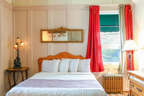 a bedroom with a bed with red curtains and a window at Hôtel-La Grande Maison et Spa in Baie-Saint-Paul