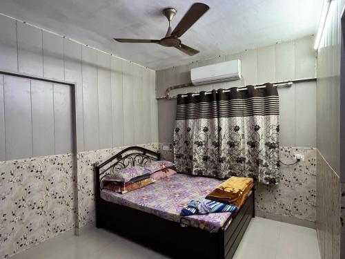 a small bedroom with a bed and a ceiling fan at Galaxy Apartment in Mumbai