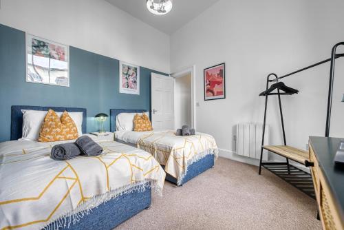 2 Bed Stunning Chic Apartment, Central Gloucester, With Parking, Sleeps 6 - By Blue Puffin Stays في غلوستر: سريرين في غرفة بجدران زرقاء