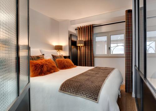 a bedroom with a large white bed with orange pillows at Le Boudoir Monsieur Aurélien - Suite Hôtelière in Le Mont-Dore