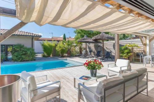 une terrasse avec des chaises blanches et une piscine dans l'établissement VILLA AMBIANCE (Pool), à Vieux-Boucau-les-Bains