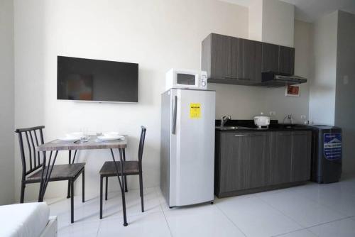 uma cozinha com um frigorífico e uma mesa com cadeiras em Comfy Studio near Shaw MRT EDSA w/ Wi-Fi & Netflix em Manila