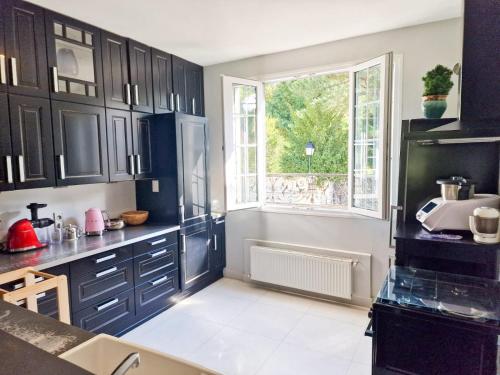 una cocina con armarios negros y una ventana en Villa Nature entre Paris et Versailles, en Marnes-la-Coquette
