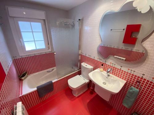 a red bathroom with a white toilet and a sink at Casa Rural Goñi in Cabañas de Ebro