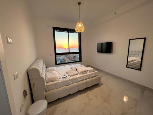 een woonkamer met een bank en een raam bij דירת 5 חדרים בבניין הכי טוב בעיר עם נוף מרהיב לים in Ashdod