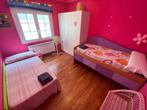 a bedroom with pink walls and a bed and a window at Casa Rural Goñi in Cabañas de Ebro