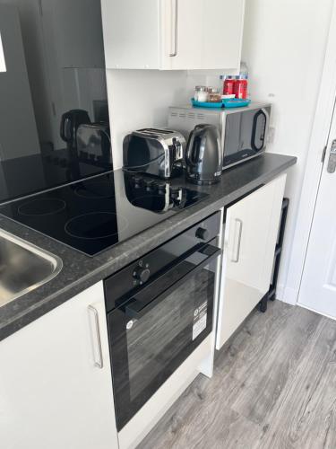 a kitchen with a stove top oven next to a sink at Modern Comfy One Bed Apartment - Free Parking in Glasgow