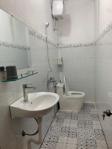 a white bathroom with a sink and a toilet at Rừng Phố Homestay And Coffee in Kon Plong