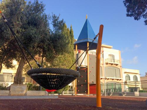 a swing in front of a building with a church at Étoile Court Apt - homey, spacious & private patio in Mġarr