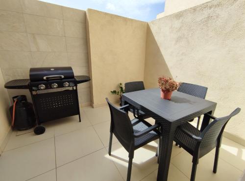 a patio with a table and chairs and a grill at Étoile Court Apt - homey, spacious & private patio in Mġarr