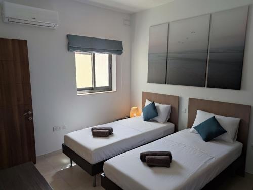 two beds in a room with a window at Étoile Court Apt - homey, spacious & private patio in Mġarr